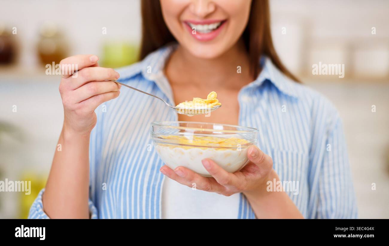 Mädchen essen Joghurt mit Flocken zum Frühstück Stockfoto