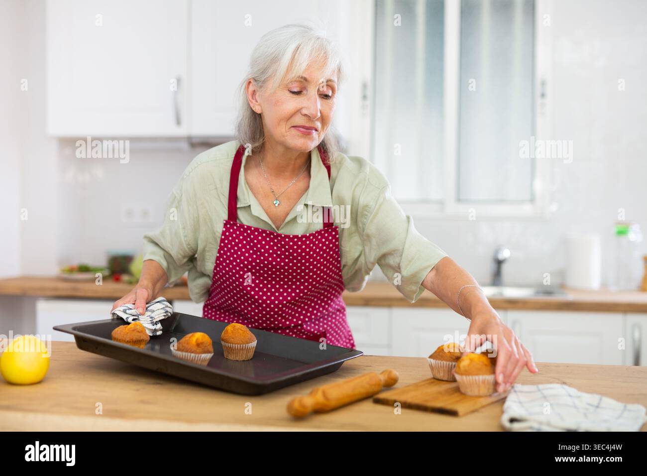 Reife Frau, die zu Hause VanilleMuffins backt Stockfoto