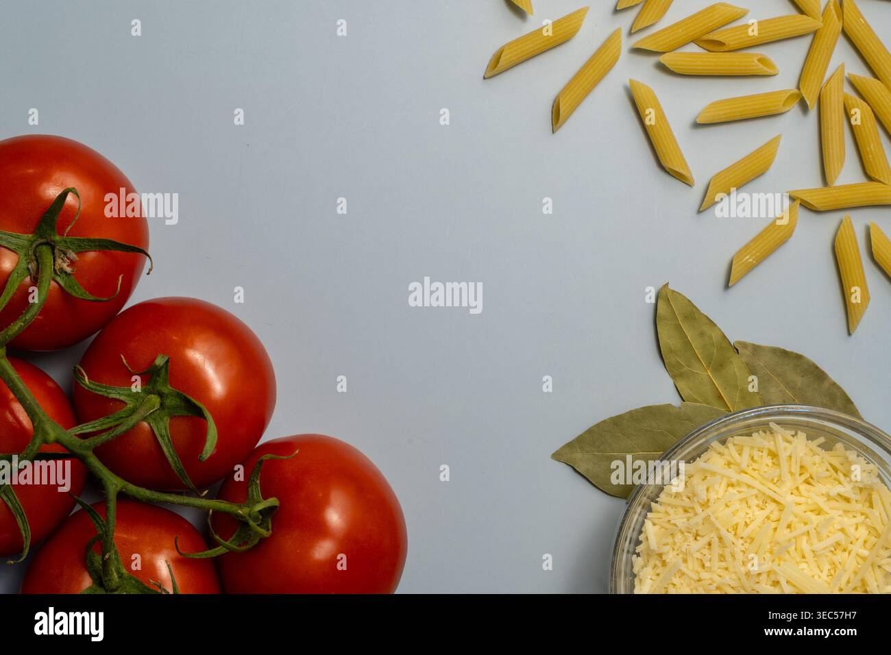 Flache Lage von Reifen Tomaten, Penne Pasta und geriebenem Parmesan auf sauberem Plain Hintergrund Stockfoto