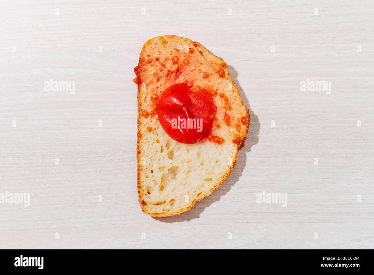 Weiches Tomatenfleisch ruht auf porösem Brot, während Feuchtigkeit und Samen sich unregelmäßig ausbreiten und das traditionelle katalanische PA amb Tomaquet mit frischen Tomaten darstellen Stockfoto