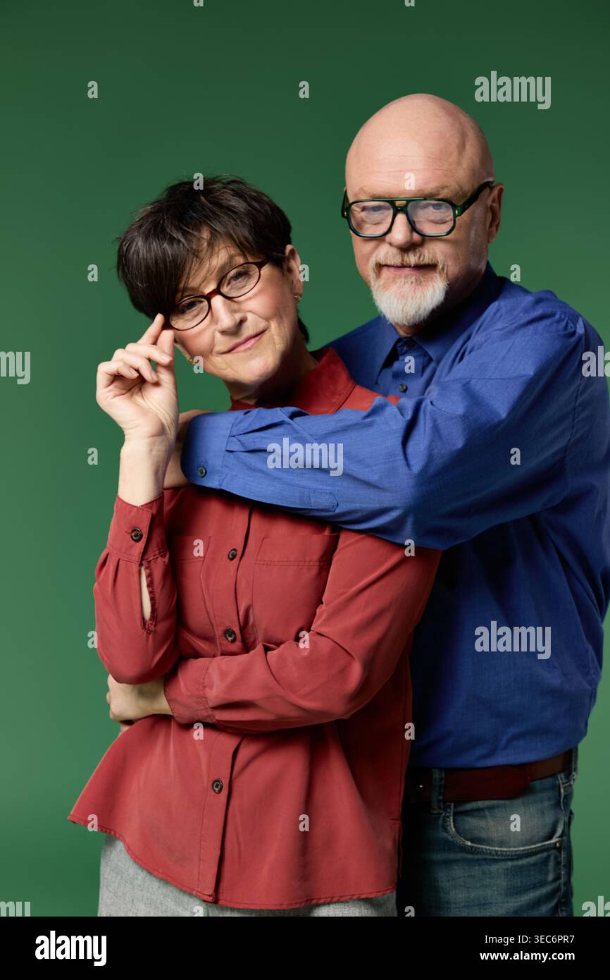 Ein freudiges Seniorenpaar teilt einen liebevollen Moment, umgeben von Grün. Stockfoto