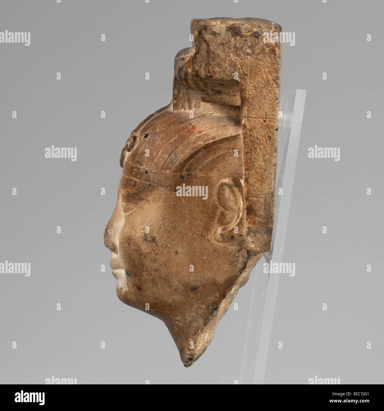 Skulpturenmodell - Kopf von Nectanebo I oder II. Skulpturenmodell in Stein, atef Krone ikonographisch, Uraeus ikonographisch, Nemes Schal ikonographisch, Hörner ikonographisch. Der Kopf des Lineals ist in voller Skulptur mit einem flachen Hintergrund verbunden, der fragmentarisch erhalten ist, nur auf der rechten Seite. Der Herrscher trägt eine Neme, die die Hälfte seiner Stirn bedeckt; seine Vorderseite ist mit einem Uräus verziert, dessen Körper in einem horizontalen Zickzack gerollt ist, ähnlich einer Acht, Schwanz gerade. Die Nemes tragen verdrehte Widderhörner. Gesicht oval und prall mit rundem Kinn und Wangen; kleiner Mund mit Ober- und Unterlippen gleich breit Stockfoto