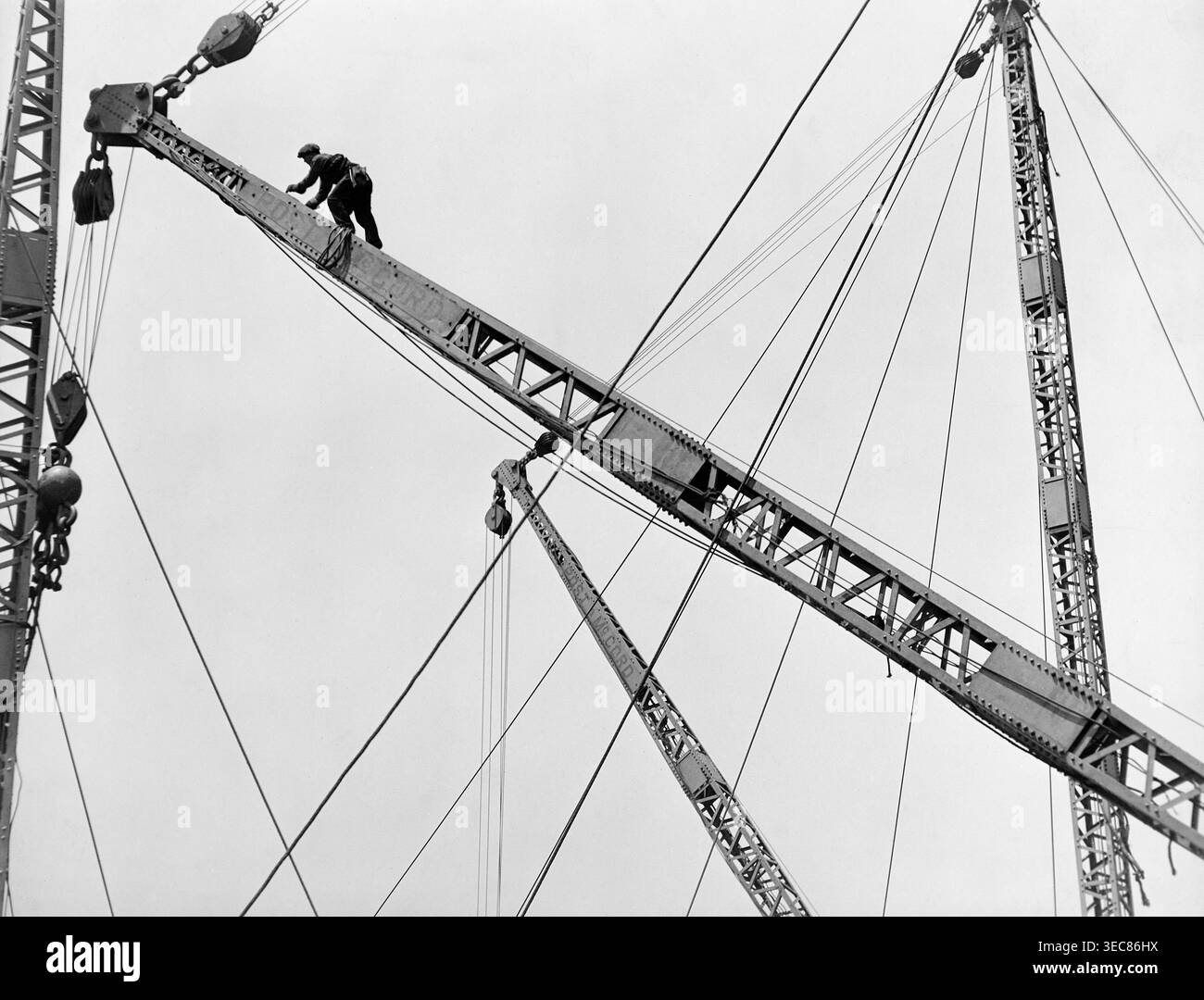 Dieses berühmte Foto aus den 1930er Jahren von Lewis W. Hine zeigt einen Bauarbeiter, der einen Derrick hoch über New York City klettert, wahrscheinlich während des Baus des Empire State Building. Das Bild, das Teil von Hines Dokumentation von „Männer bei der Arbeit“ ist, unterstreicht den Mut und das Können der Arbeiter, die am Bau großer städtischer Infrastrukturen beteiligt sind. Stockfoto