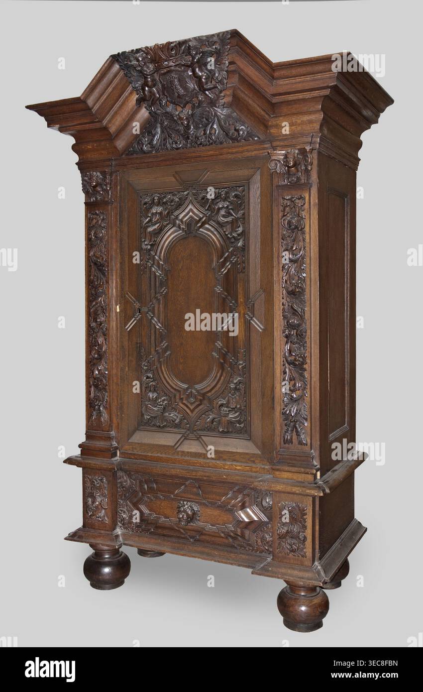 Garderobe, Provenienz, Putti; Barock; Wappen; Pflanzendekoration; Löwenmasken; Personifizierungen der Jahreszeiten: Frühling, Sommer, Herbst, Winter; 1710–1730; Gdańsk, Königlich Preußen; Möbelaufbewahrung; Höhe 200 cm, Breite 124 cm, Tiefe 62 cm, Ein großer kunstvoller Holzschrank steht vor einem hellgrauen Hintergrund, geschnitzt aus dunkelbraunem Holz mit satter Maserung. Der Schrank verfügt über ein überhängendes Gesims mit Stufenleiste und ein kunstvoll geschnitztes Wappen mit Blumen- und Blättermotiven. Die Mitteltür hat eine vertiefte Platte mit symmetrischen geschnitzten Ornamenten, einschließlich geschwungener Bogenformen Stockfoto
