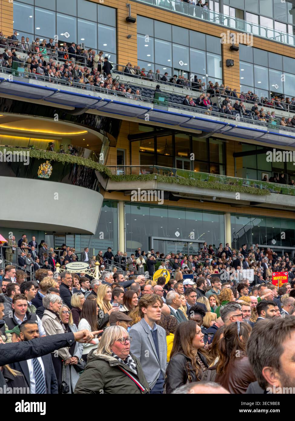 Menschenmassen beobachten das Pferderennen vor der Tribüne auf dem Ascot Rennkurs am British Champions Day, Ascot, UK Stockfoto