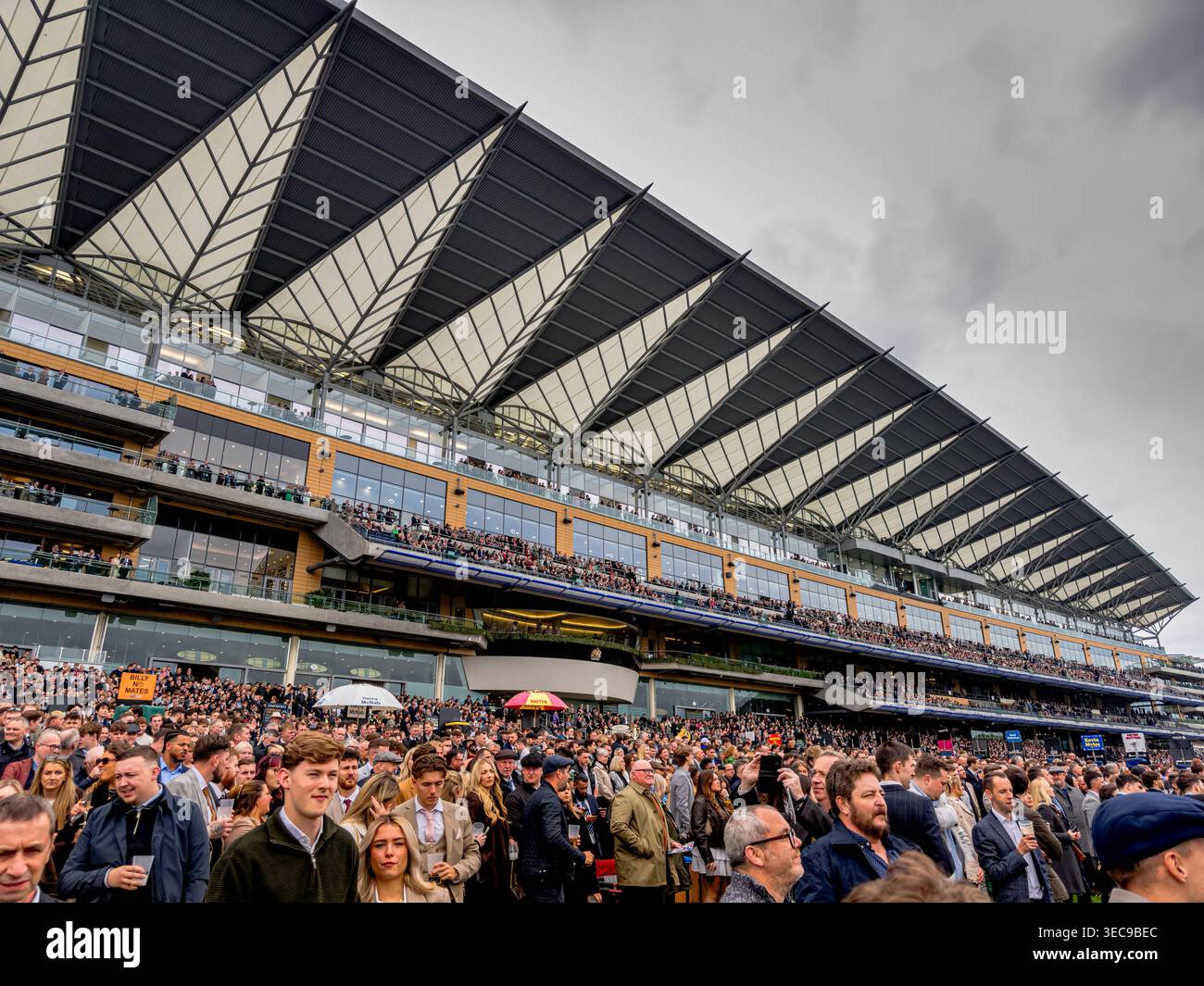 Menschenmassen beobachten das Pferderennen vor der Tribüne auf dem Ascot Rennkurs am British Champions Day, Ascot, UK Stockfoto