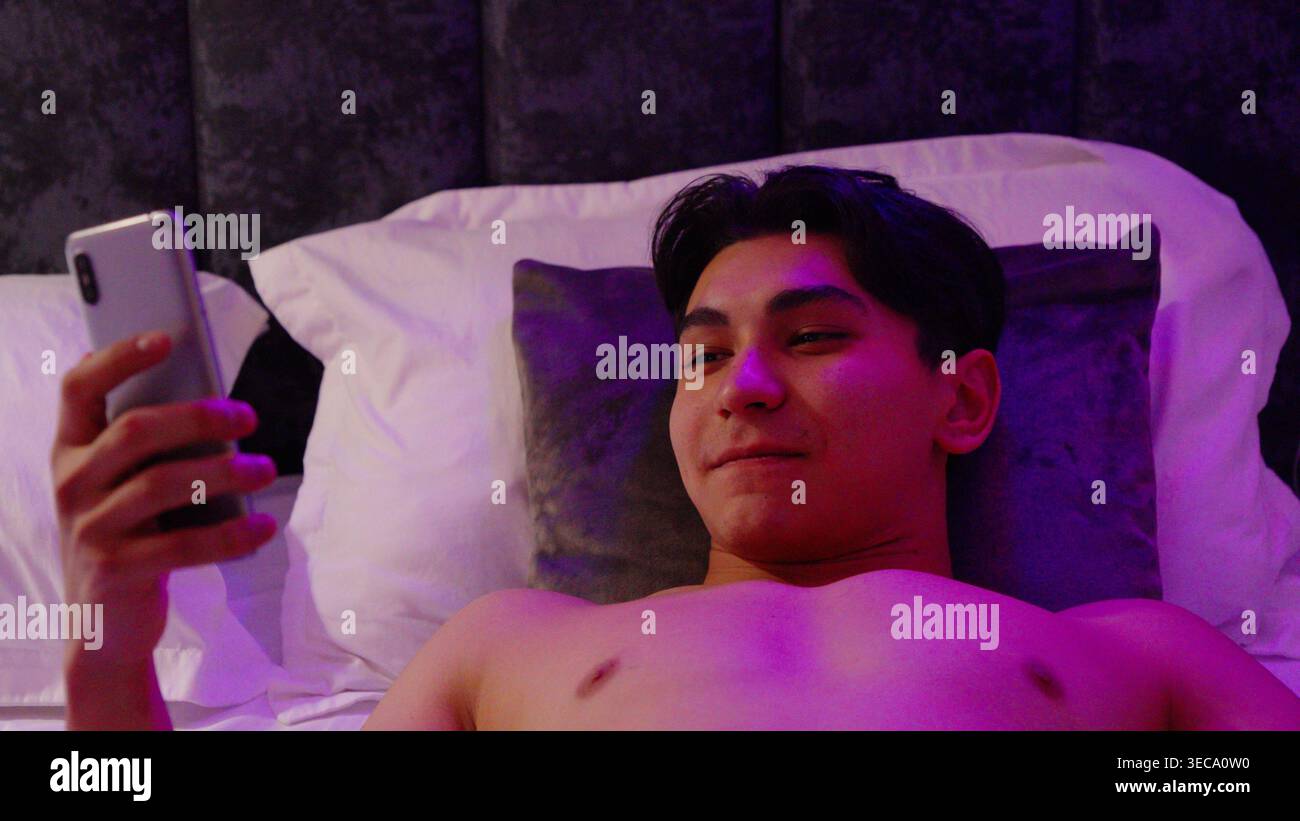 Mann, der im Bett liegt und Smartphone benutzt Stockfoto