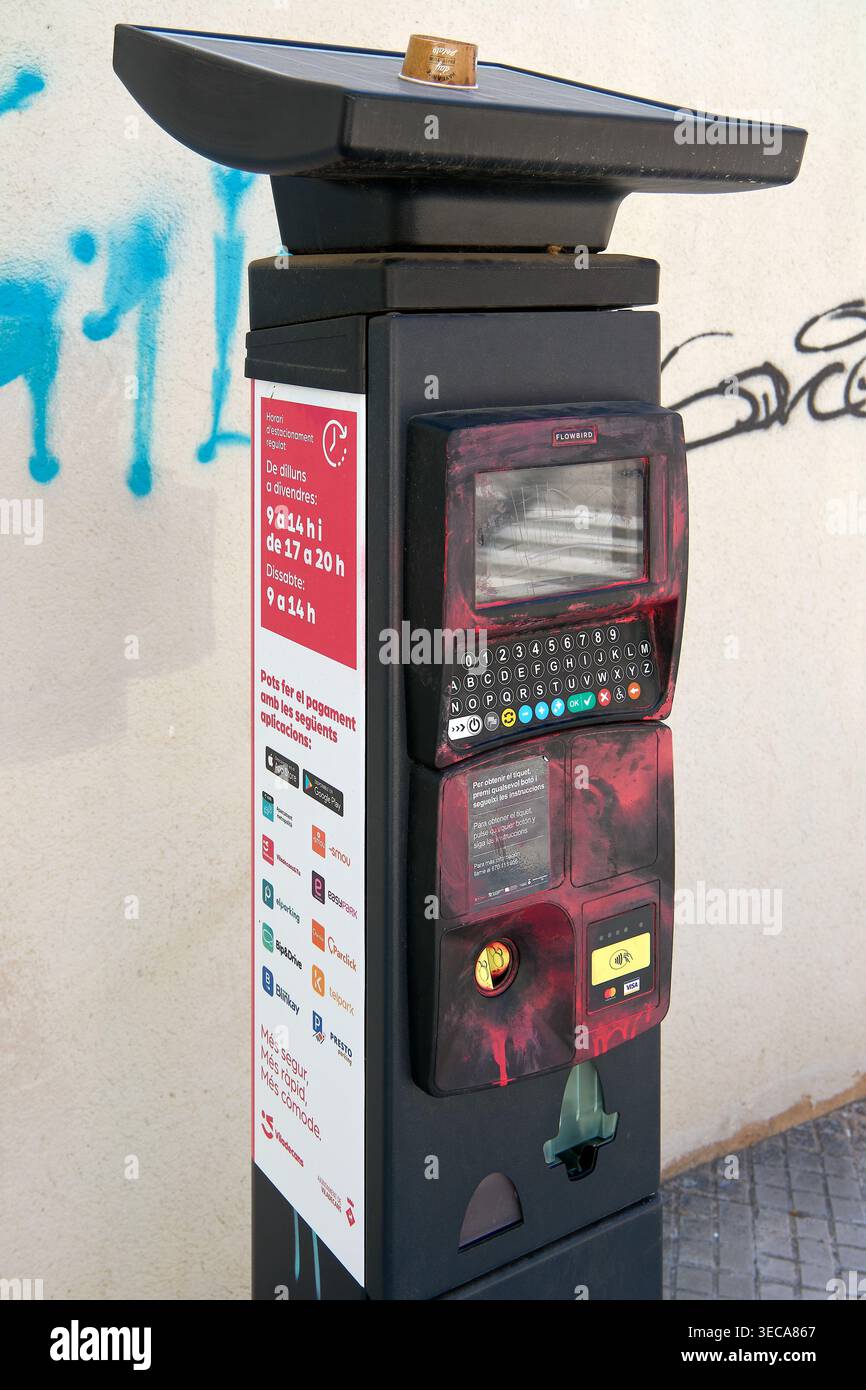 Viladecans, Spanien - 29. April 2026: Auf einem Bürgersteig in Viladecans steht ein digitaler Parkzähler mit rotem Lackvandalismus Stockfoto