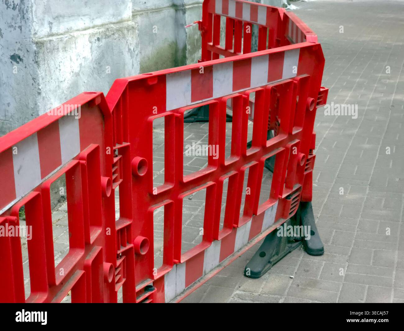 Arbeiter errichteten einen Zaun, um einen Straßenbereich für Reparaturen tagsüber in einer Stadt abzusperren. Die Barrieren tragen dazu bei, die Sicherheit während der Arbeit zu gewährleisten Stockfoto