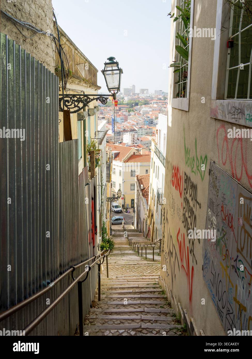Enge Treppenstraße in Lissabon, Portugal, gesäumt von historischen Gebäuden und mit Blick auf die farbenfrohe Skyline der Stadt. Stockfoto