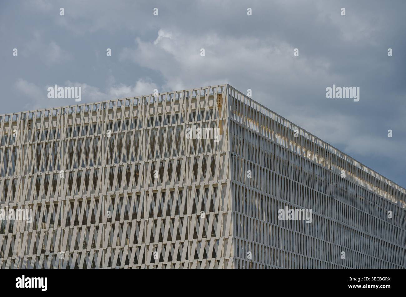 Modernes Gebäude mit geometrischer Gitterfassade unter bewölktem Himmel Stockfoto