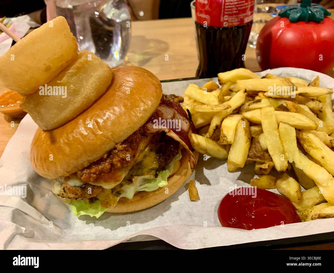 Ein Hähnchen-, Rind- und Lammfleisch-Burger mit Zwiebelringen und Pommes frites - Smartphone-aufgenommenes Stockfoto
