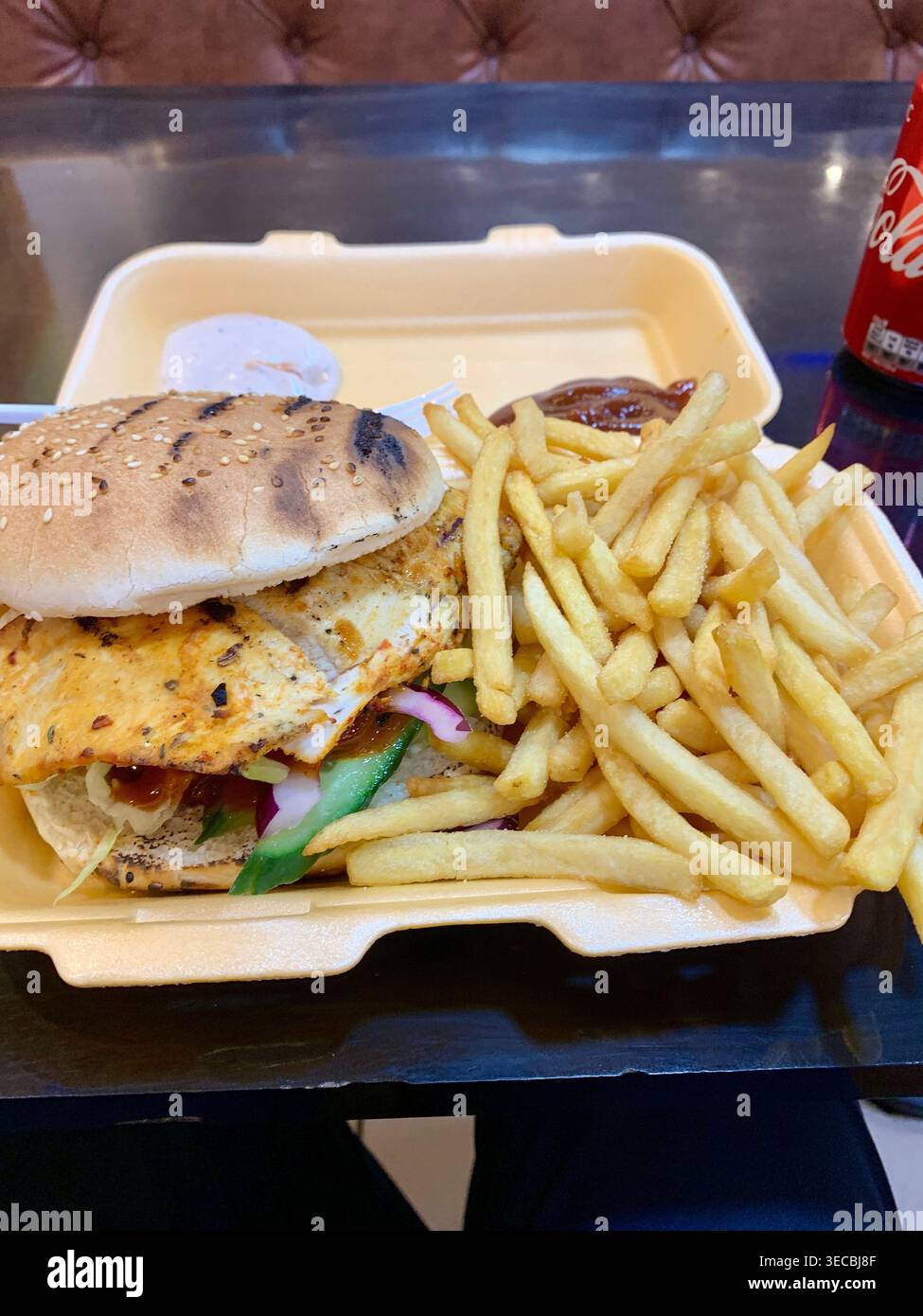 Ein gegrillter Hähnchenburger mit Pommes und einem Getränk - Smartphone-aufgenommenes Stockfoto