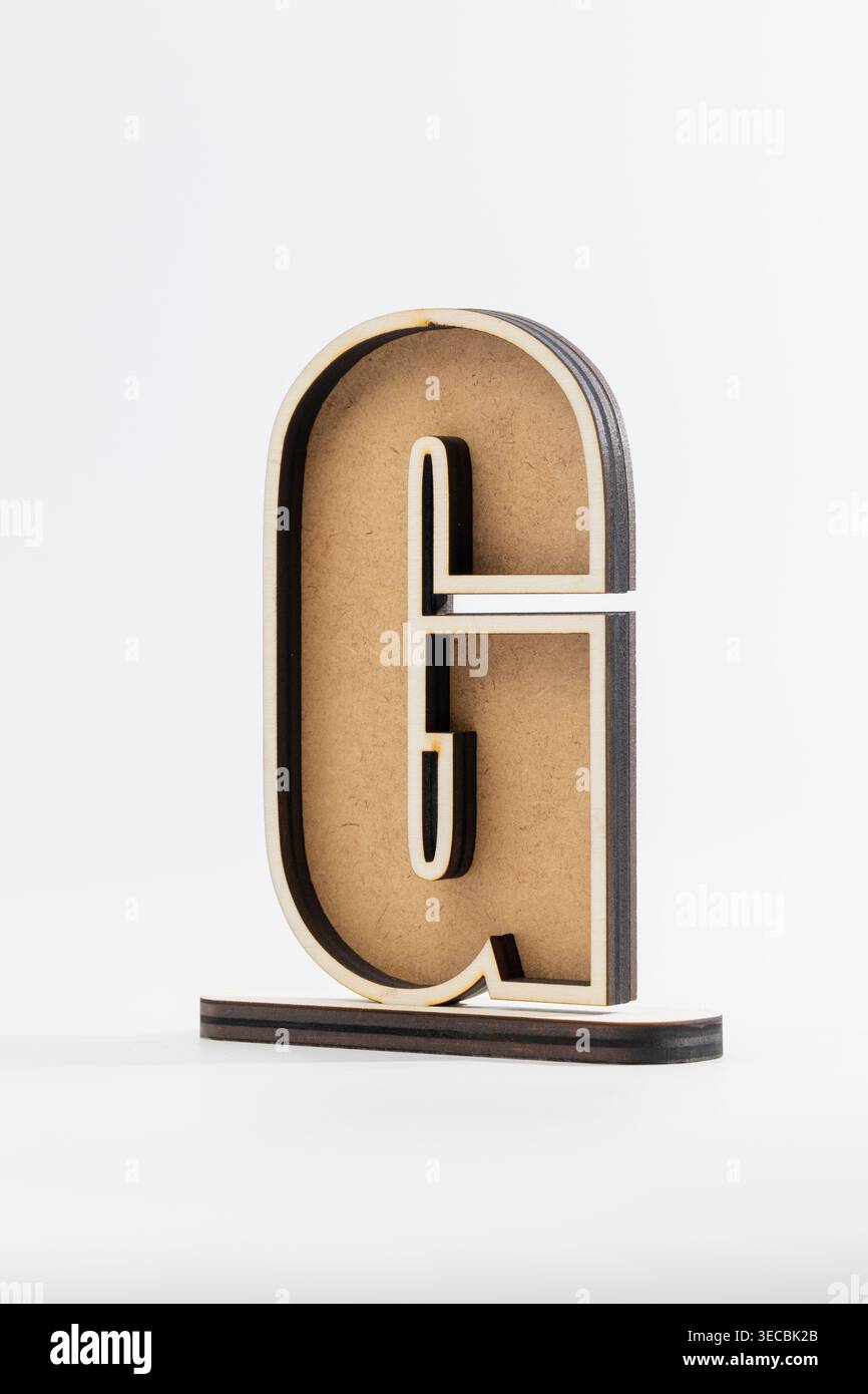 Minimalistischer Buchstabe „G“ aus mehrschichtigen Holztönen. Klare Linien stehen im Kontrast zu strukturierten Oberflächen. Das schlanke Design steht auf einer passenden Basis. Moderne aes Stockfoto