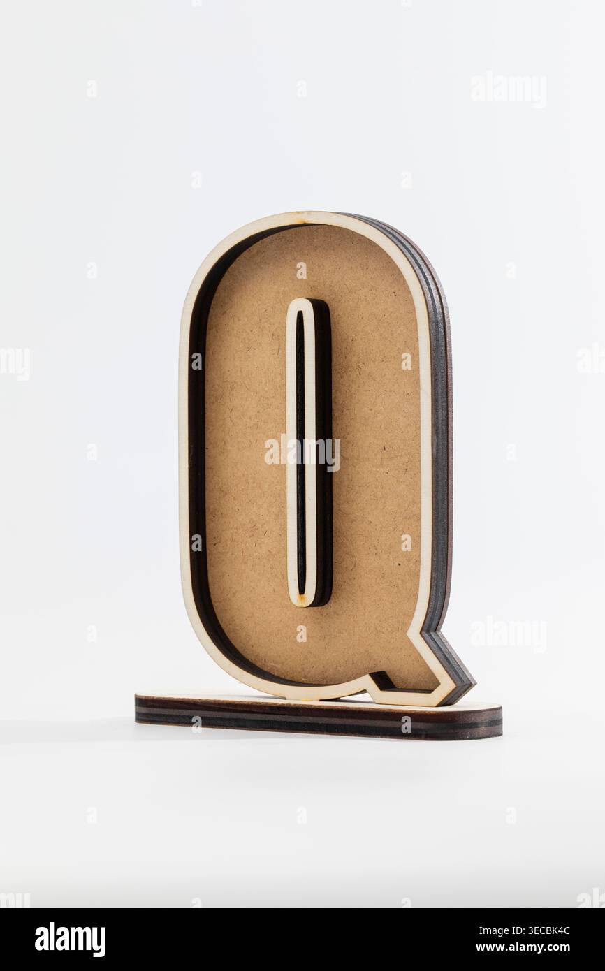 Der Holzbuchstabe Q steht hoch und kräftig. Das einfache, saubere Design unterstreicht die natürliche Struktur der Körnung. Dezenter Schatten verleiht minimalistischen Hintergründen Tiefe. Modern Stockfoto