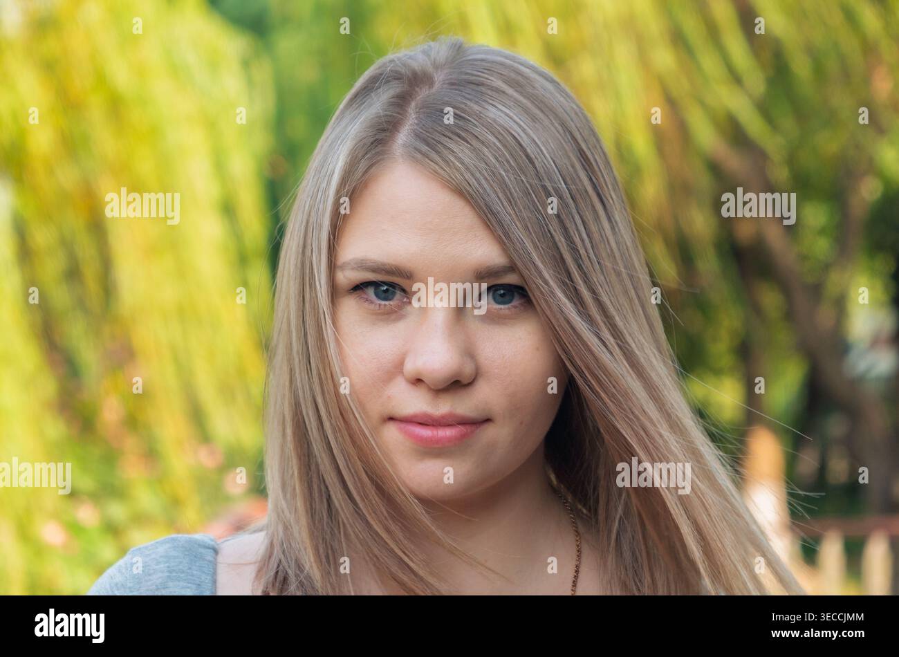 Kopfaufnahme einer jungen Frau mit glatten hellblonden Haaren und blauen Augen im Freien in natürlichem Licht Stockfoto