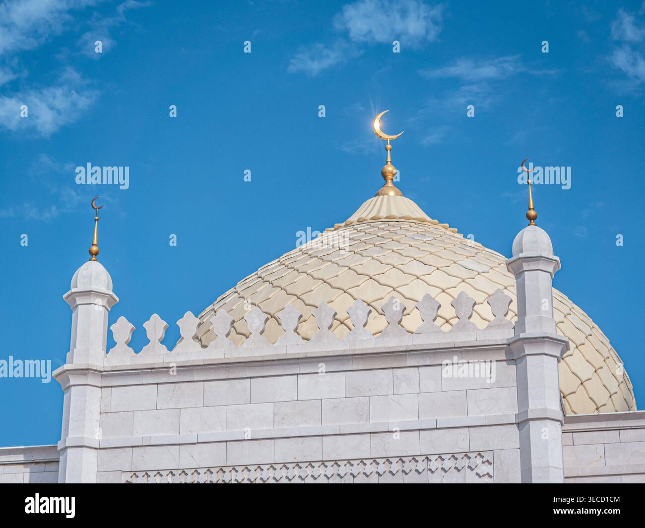 Goldene Kuppel und halbmondförmige Finiale auf einer großen weißen Moschee unter einem hellblauen Himmel Stockfoto