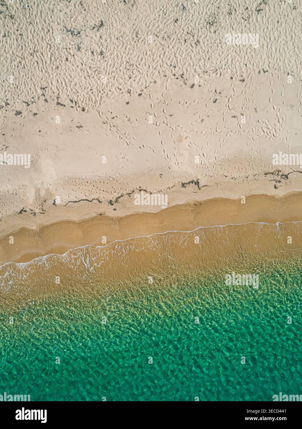 Meereswellen treffen sanft auf sanfte Sandstrände mit klarem türkisfarbenem Wasser und goldenem Strand von oben Stockfoto