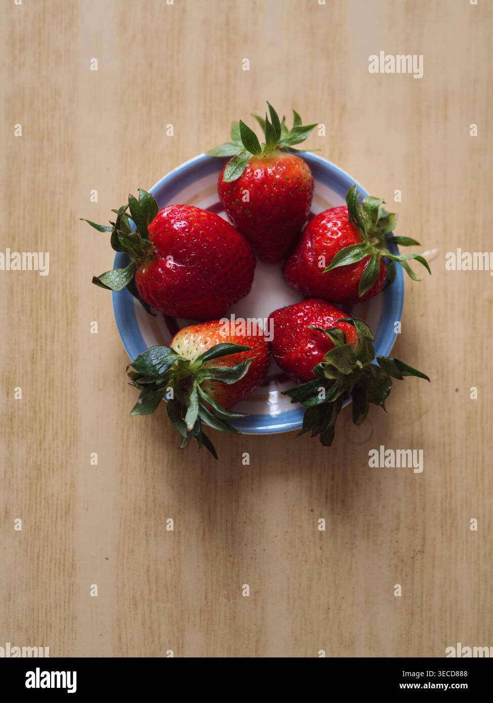 Fünf Erdbeeren auf einem Teller auf Holztablett, vertikale Flat Lay Stockfoto