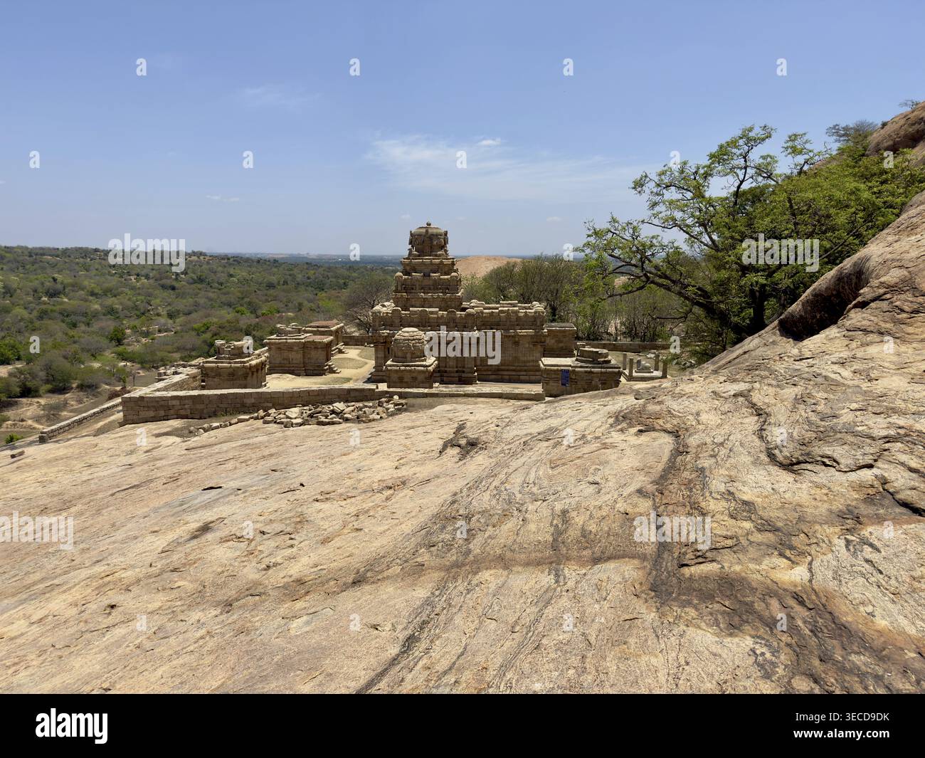 Steintempel in einer felsigen, bewaldeten Umgebung unter einem hellblauen Himmel, Vijayalaya Choleeswaram Tempel, Tamil Nadu, Indien Stockfoto