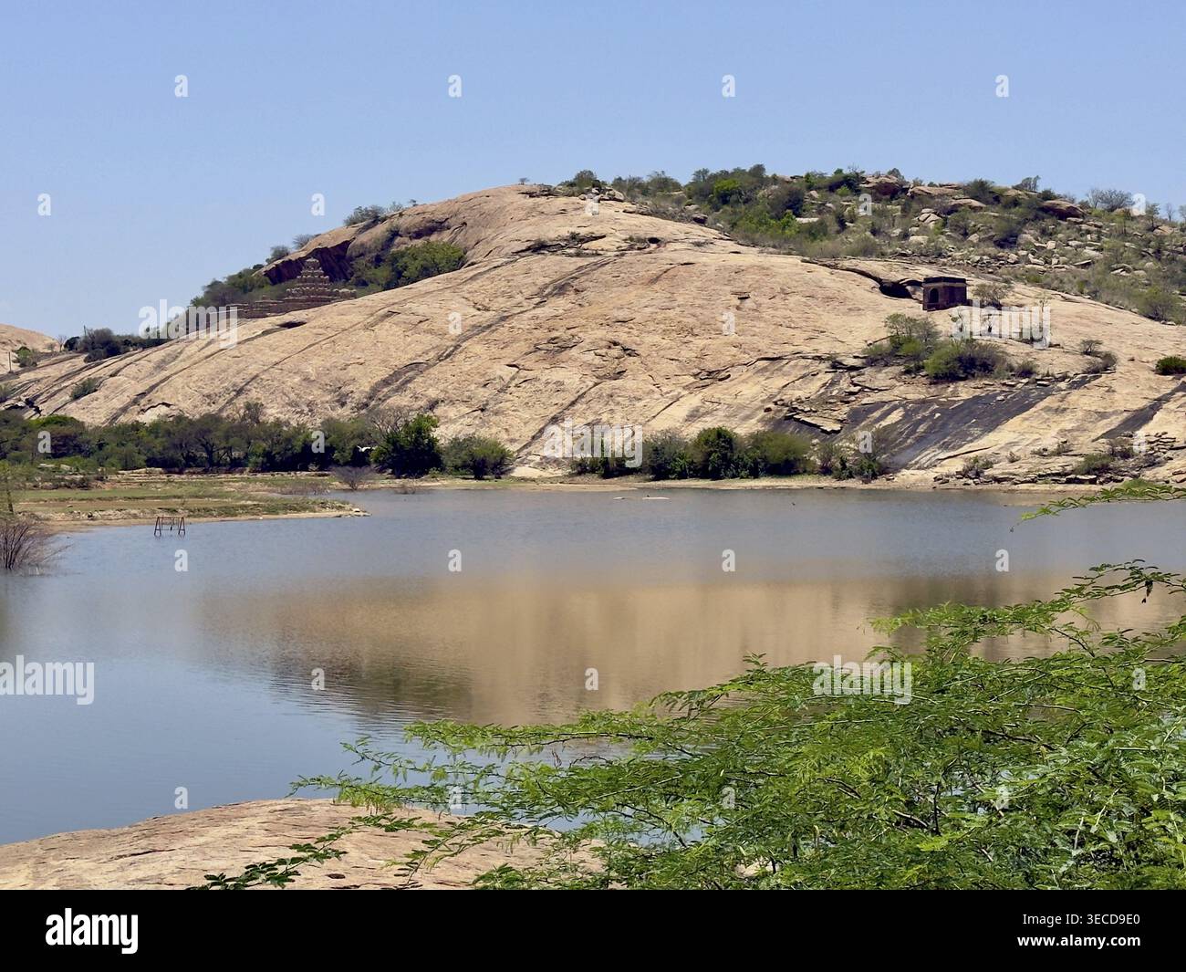 Ruhiger See umgeben von Felsen und grüner Vegetation, mit Hügeln im Hintergrund, Vijayalaya Choleeswaram Tempel, Tamil Nadu, Indien Stockfoto
