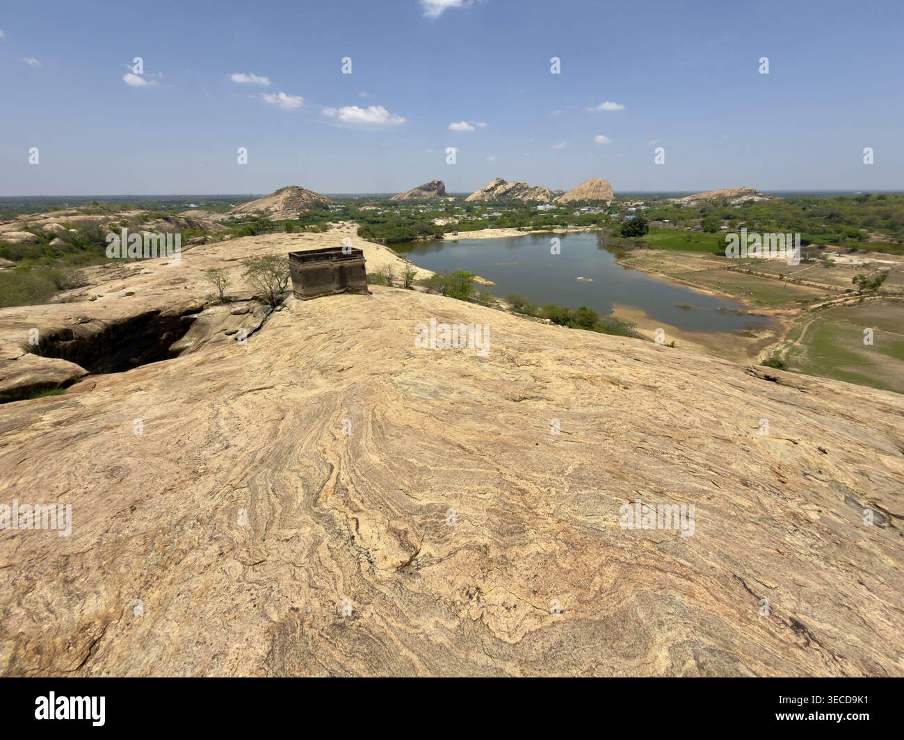 Weite felsige Landschaft mit Blick auf einen See und ferne Hügel unter einem klaren blauen Himmel, Vijayalaya Choleeswaram Tempel, Tamil Nadu, Indien Stockfoto