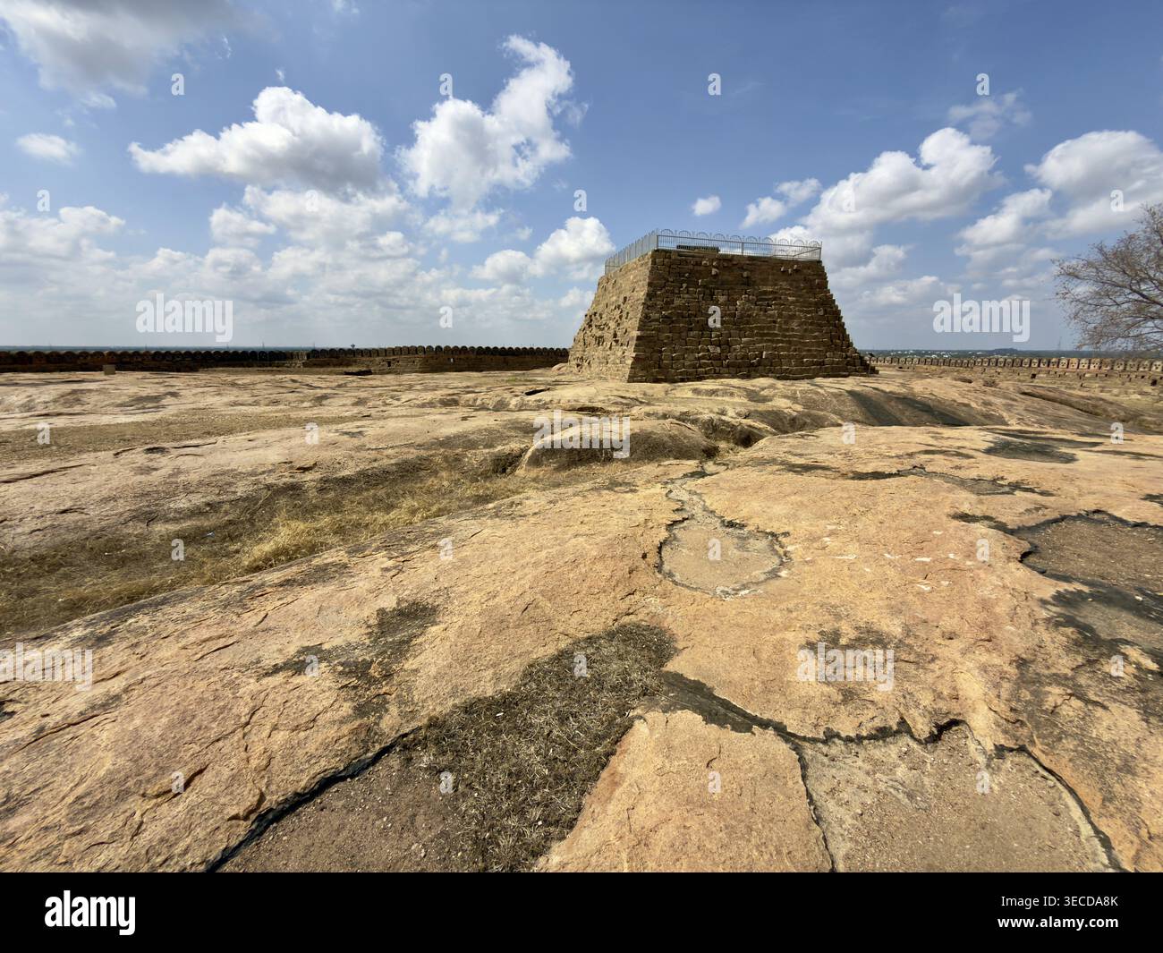 Steinstruktur auf einem weiten, felsigen Gebiet unter blauem Himmel mit Wolken, Thirumayam Fort, Thirumayam, Tamil Nadu, Indien Stockfoto