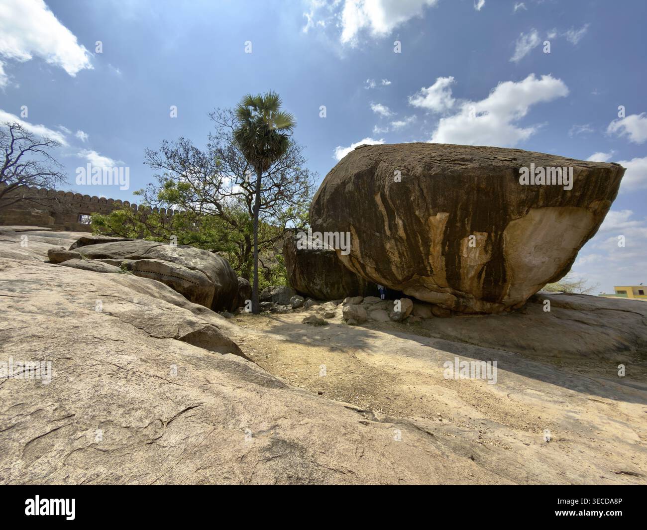 Massive Felsformation mit Mauer im Hintergrund, blauer Himmel, Thirumayam Fort, Thirumayam, Tamil Nadu, Indien Stockfoto