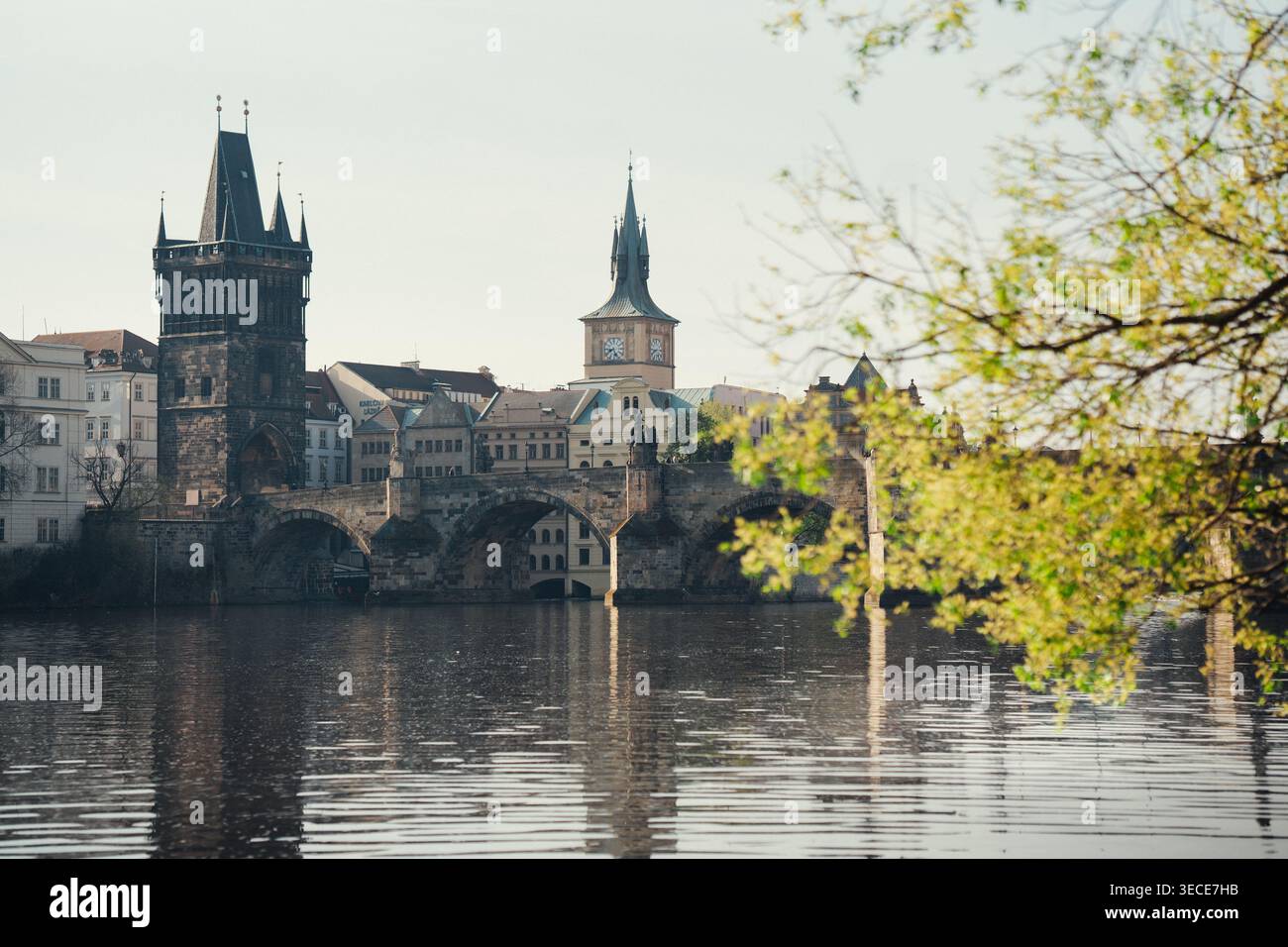 Blick auf historische Gebäude in der Nähe der Karlsbrücke in Prag, sonniger Tag mit Reflexionen im Wasser Stockfoto