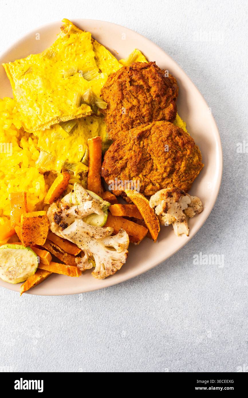 Ein lebhafter Teller mit flauschigem gelbem Reis, cremigen Rhabarber-Spiegeleiern und knusprigen Fleischgerichten bietet eine herzhafte und geschmackvolle Mahlzeit, die perfekt für einen ist Stockfoto