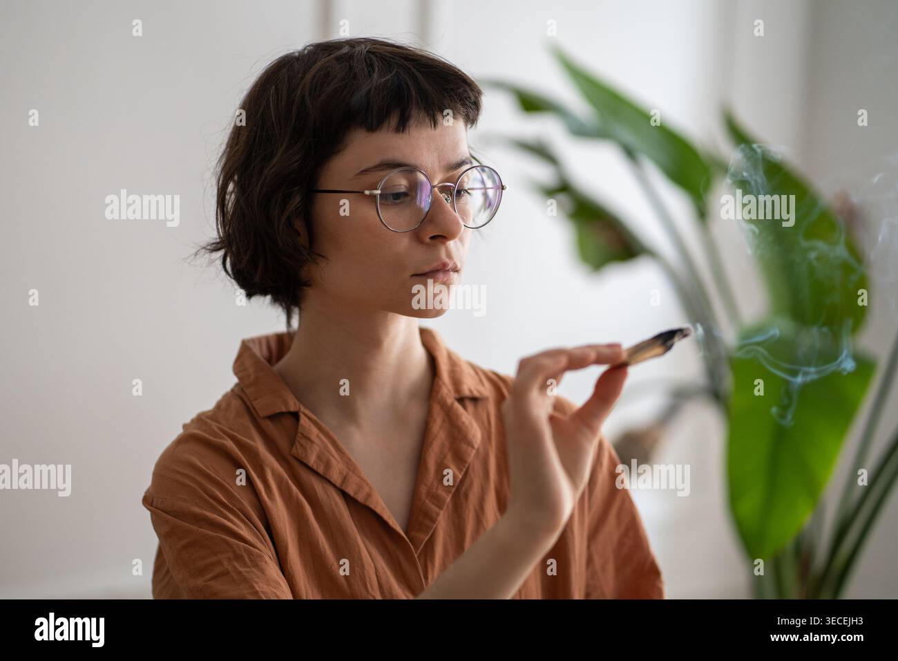 Eine ruhige Frau, die zu Hause den aromatischen palo santo-Schmutzstab für Sinnestherapie und Meditation beleuchtet Stockfoto