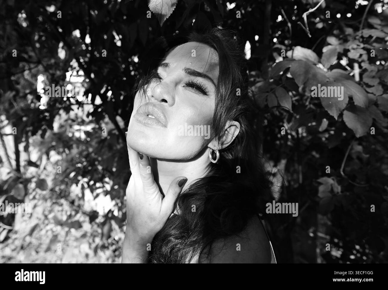 Eine Sängerin/Model/Schauspielerin nimmt sich einen Moment Zeit, um im Garten unter den Bäumen zu entspannen und über das Leben ... nachzudenken Stockfoto