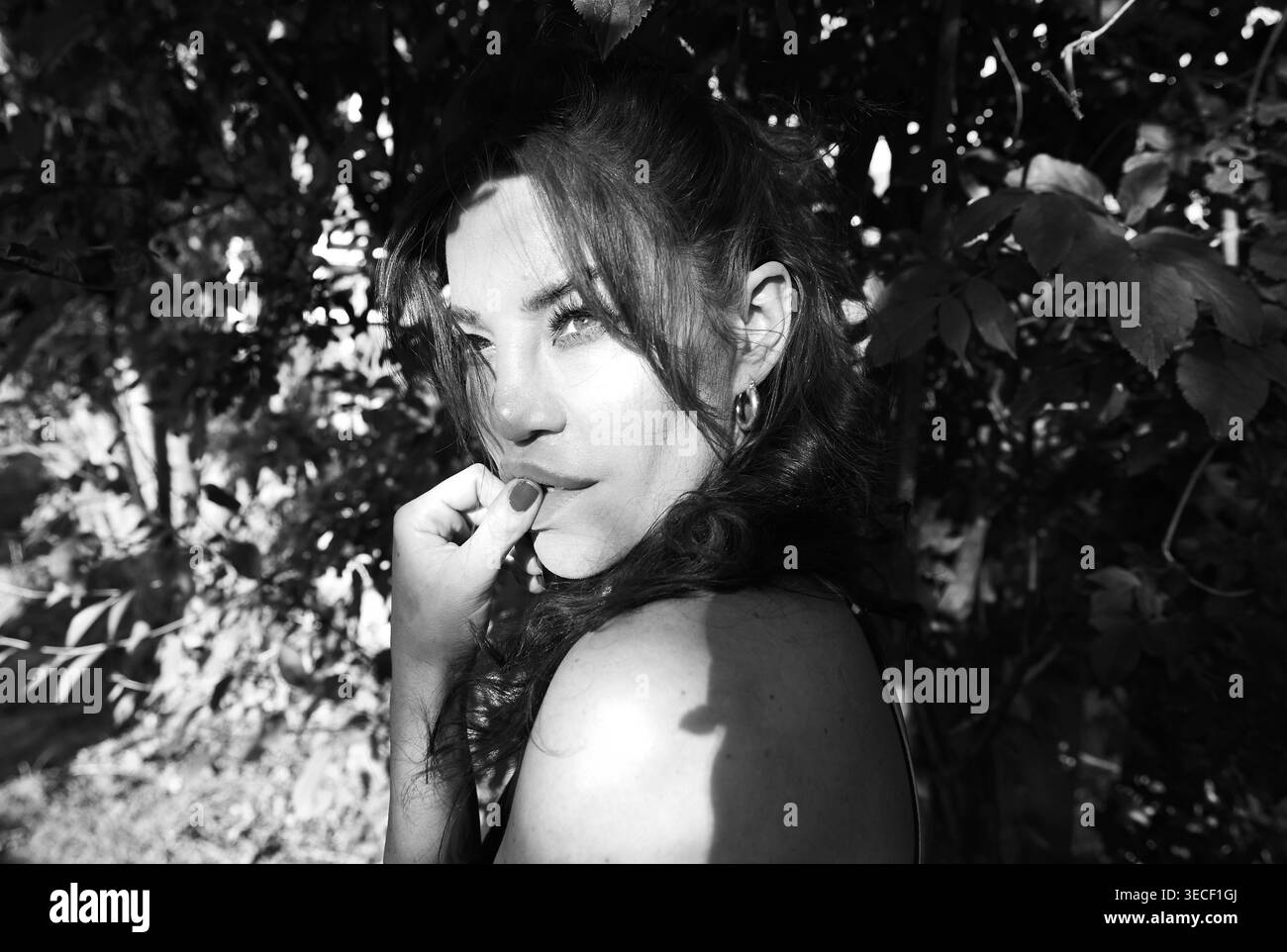 Eine Sängerin/Model/Schauspielerin nimmt sich einen Moment Zeit, um im Garten unter den Bäumen zu entspannen und über das Leben ... nachzudenken Stockfoto