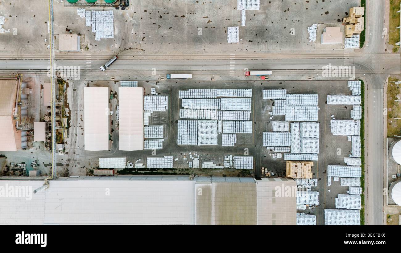Aus der Vogelperspektive organisierte weiße Paletten in einem Industrielager mit LKW und großen Fabrikgebäuden in Sabac, Vojvodina, Serbien. Stockfoto