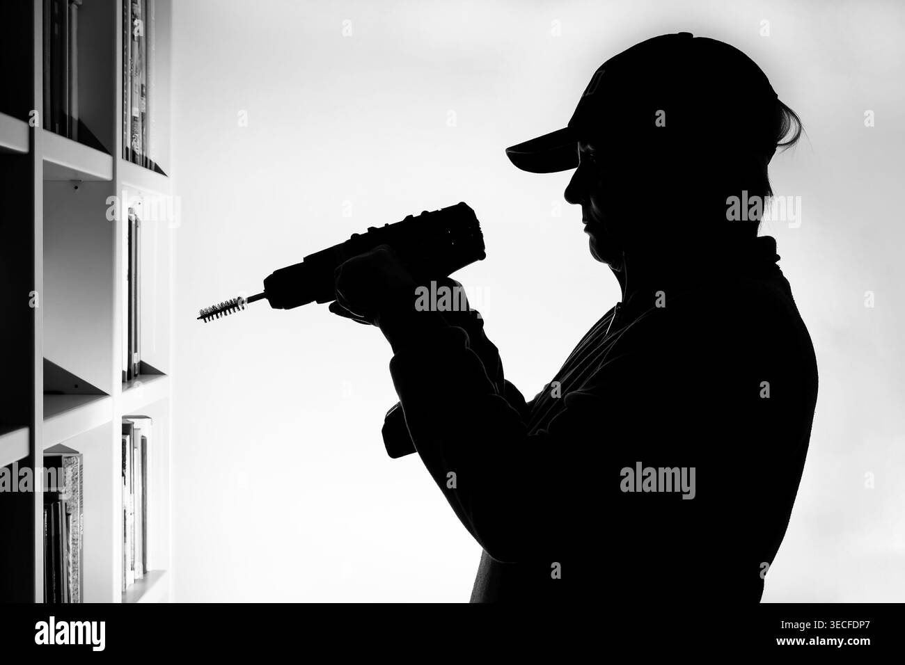 Silhouette einer Frau, die einen Bohrschrauber in einer häuslichen Umgebung benutzt Stockfoto
