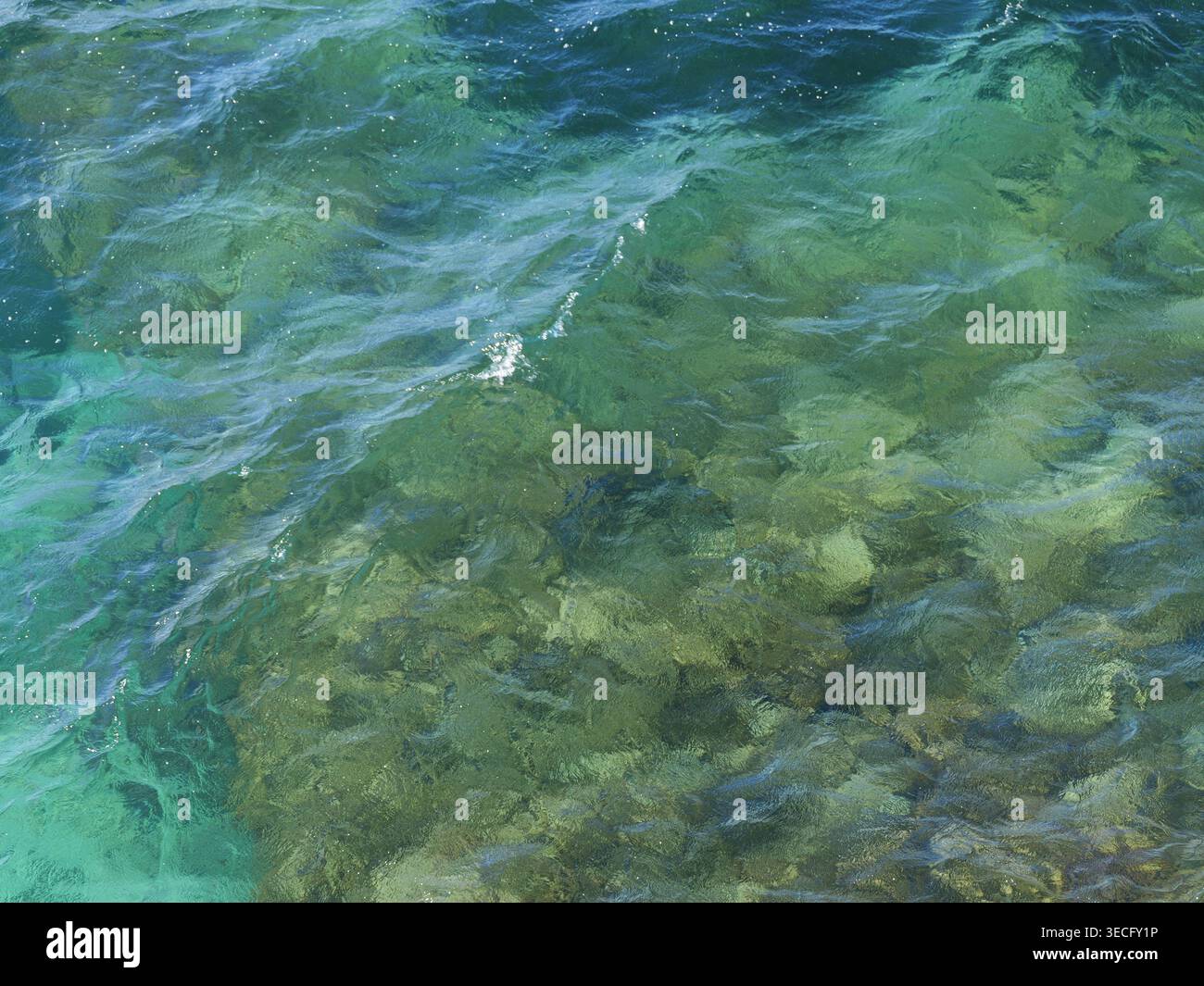 Mediterranes Meerwasser mit leuchtendem Türkis und sanften Wellen über dem felsigen Meeresboden. Draufsicht. Kopierbereich. Stockfoto
