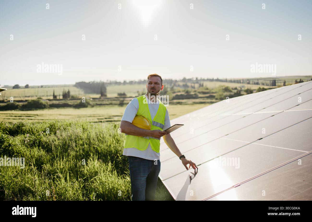 Ein glücklicher Arbeiter testet Solarpaneele mit Tablet Stockfoto