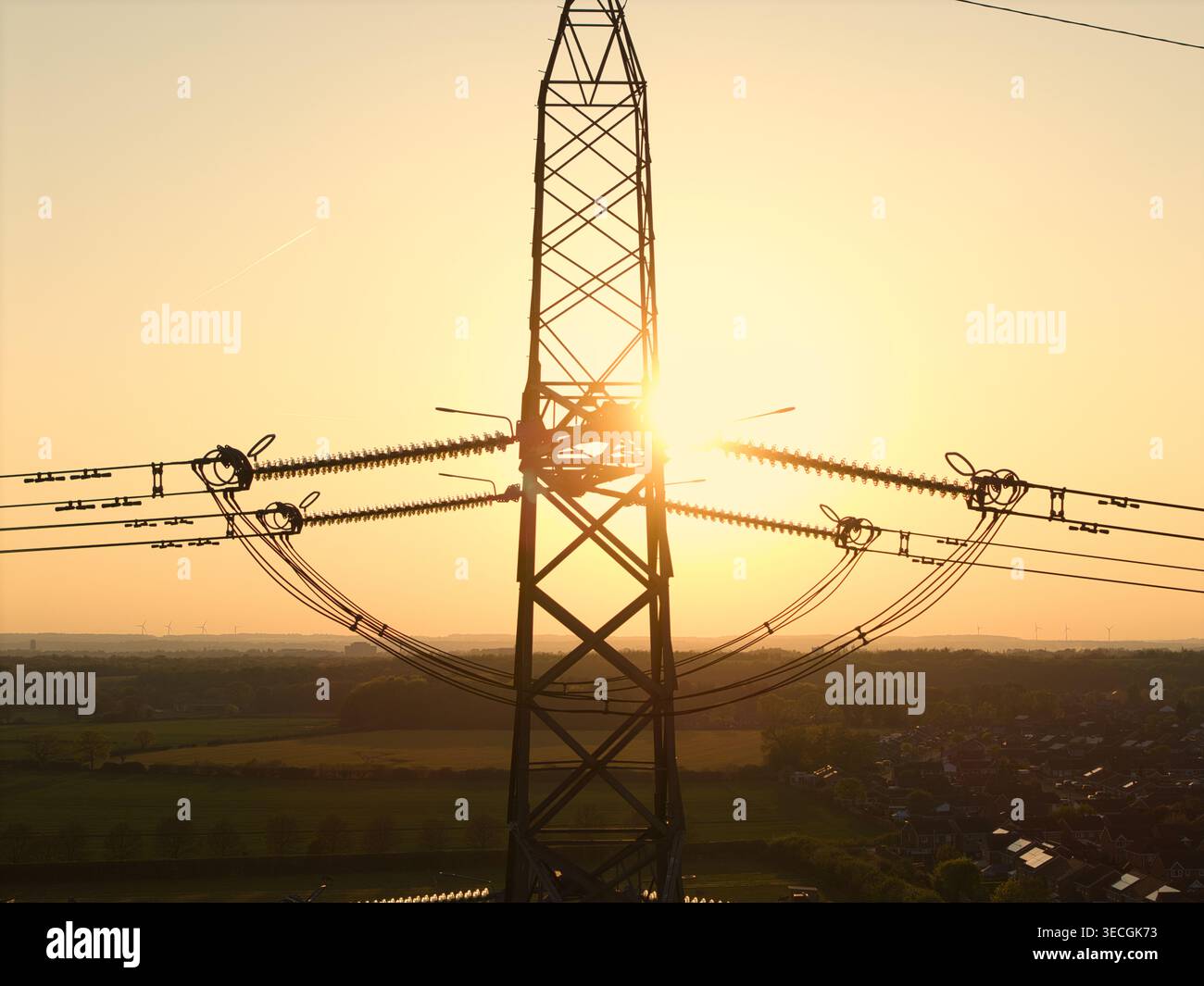 Aus der Vogelperspektive eines elektrischen Pylons vor einem goldenen Sonnenuntergang über grünen Feldern und Wohnhäusern Armthorpe, England, Großbritannien. Stockfoto
