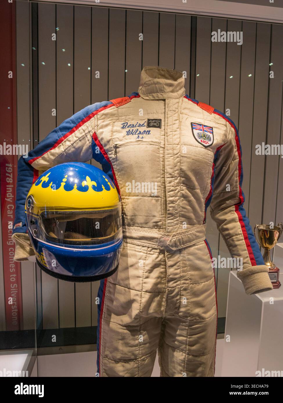 Rennanzug und Helm (1983) von Desire Wilson im Silverstone Museum, Silverstone Circuit, Silverstone, Towcester, Großbritannien. Stockfoto