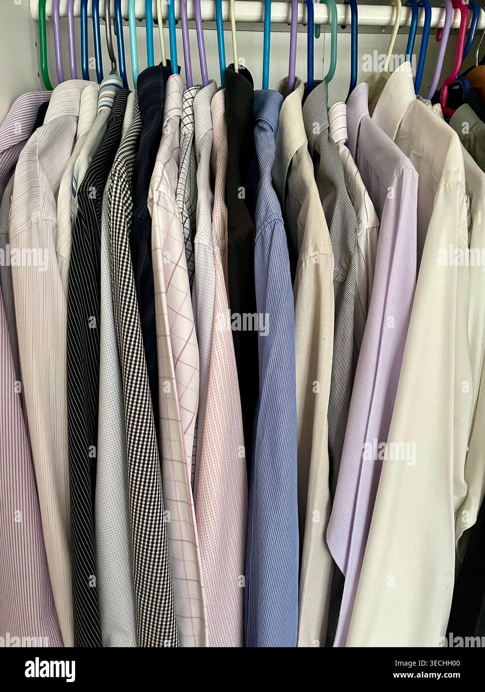 Eine Sammlung von professionellen Hemden in verschiedenen Farben auf farbigen Kleiderbügeln - Smartphone-aufgenommenes Stockfoto