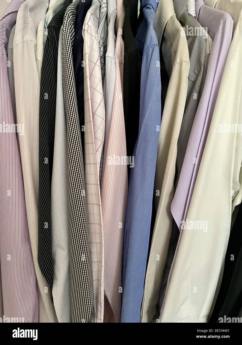 Eine Sammlung von professionellen Hemden in verschiedenen Farben auf farbigen Kleiderbügeln - Smartphone-aufgenommenes Stockfoto