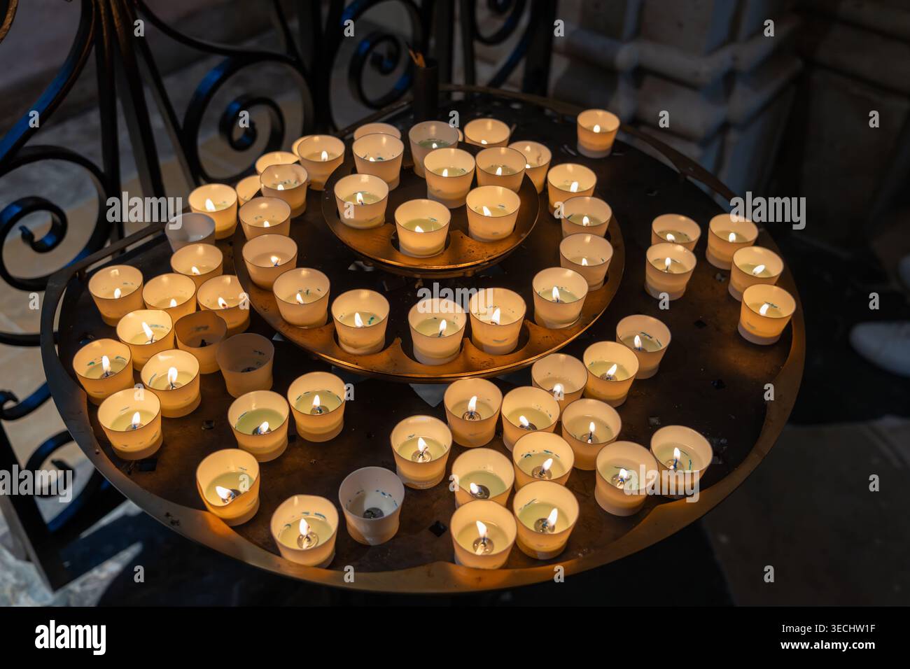Kreisförmiges Tablett mit Reihen beleuchteter Erinnerungskerzen in der Kathedrale Notre Dame Stockfoto
