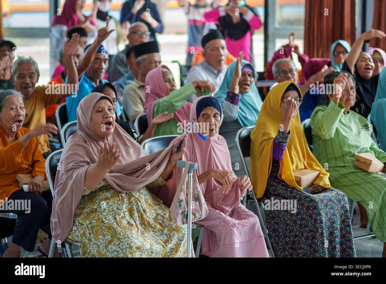 Eine Gruppe älterer Bewohner, die begeistert an einer gemeinsamen Aktivität im PPSLU Mandalika in Mataram, Indonesien, teilnehmen. Stockfoto