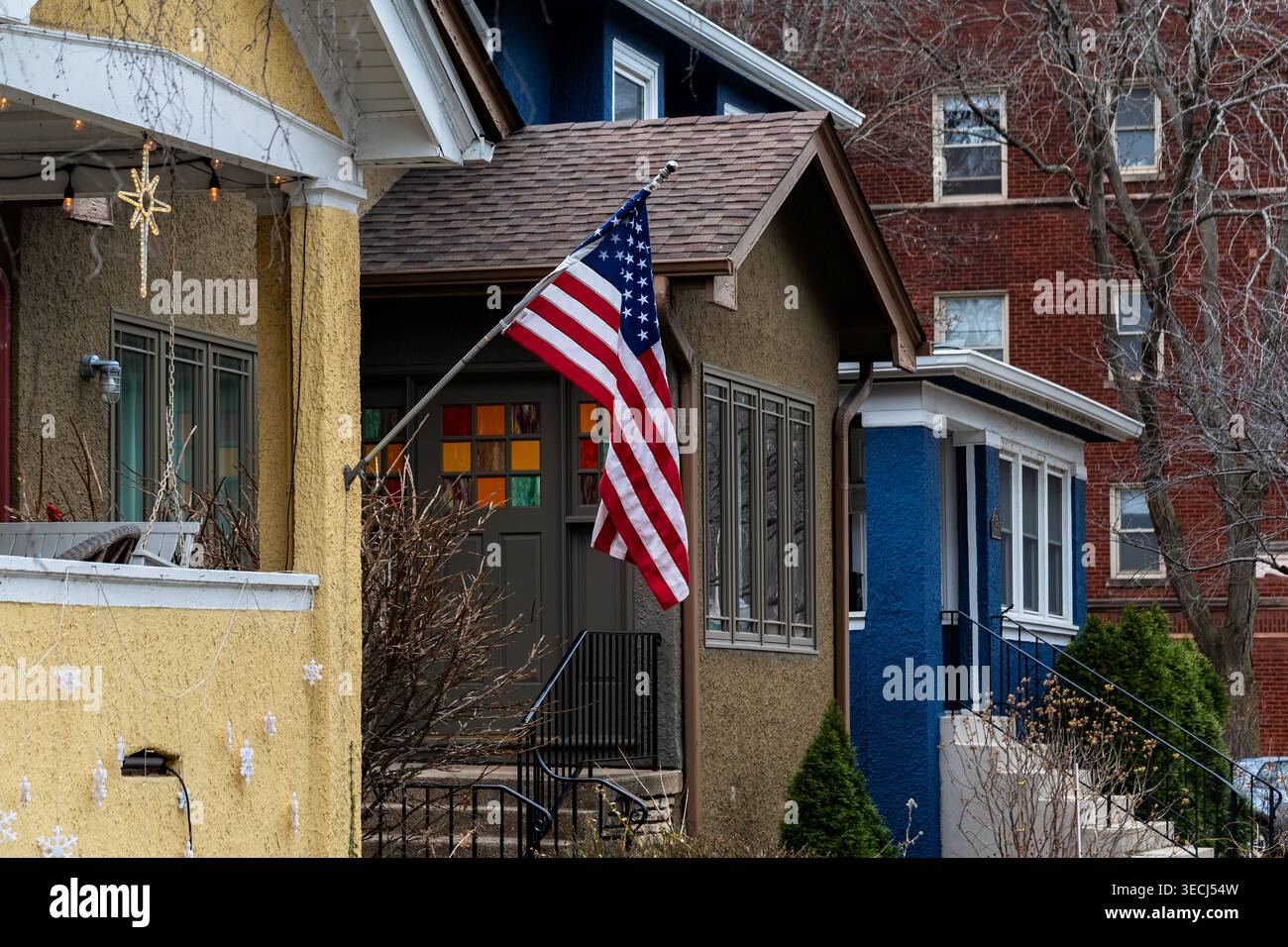 Die amerikanische Flagge fliegt von einem Fahnenmast an der gelben Wand eines Hauses in Chicago. Stockfoto