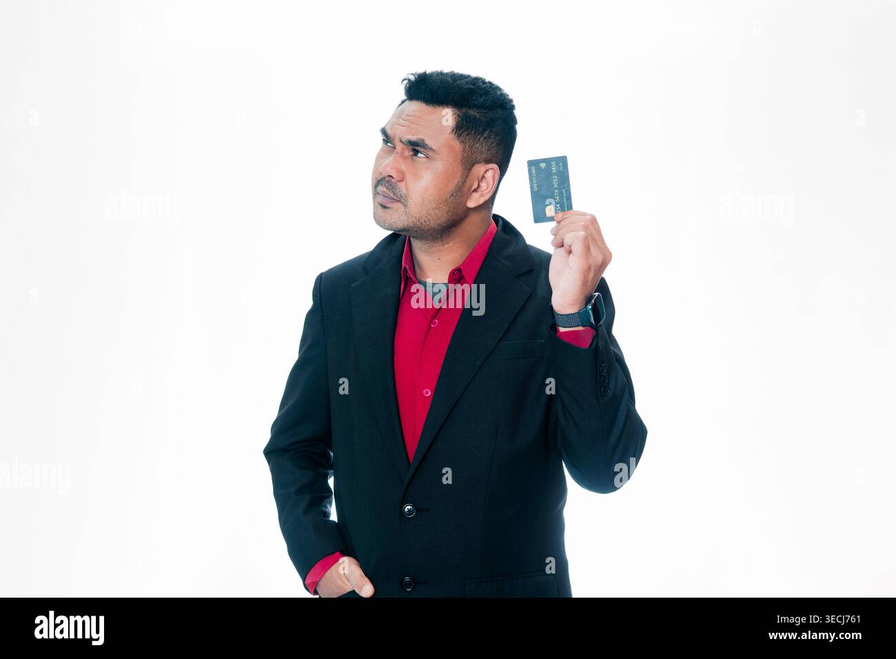 Porträt eines indonesischen Berufsmannes im Anzug, der nachdenklich aussieht und eine Kreditkarte hält, isoliert auf weißem Hintergrund. Stockfoto