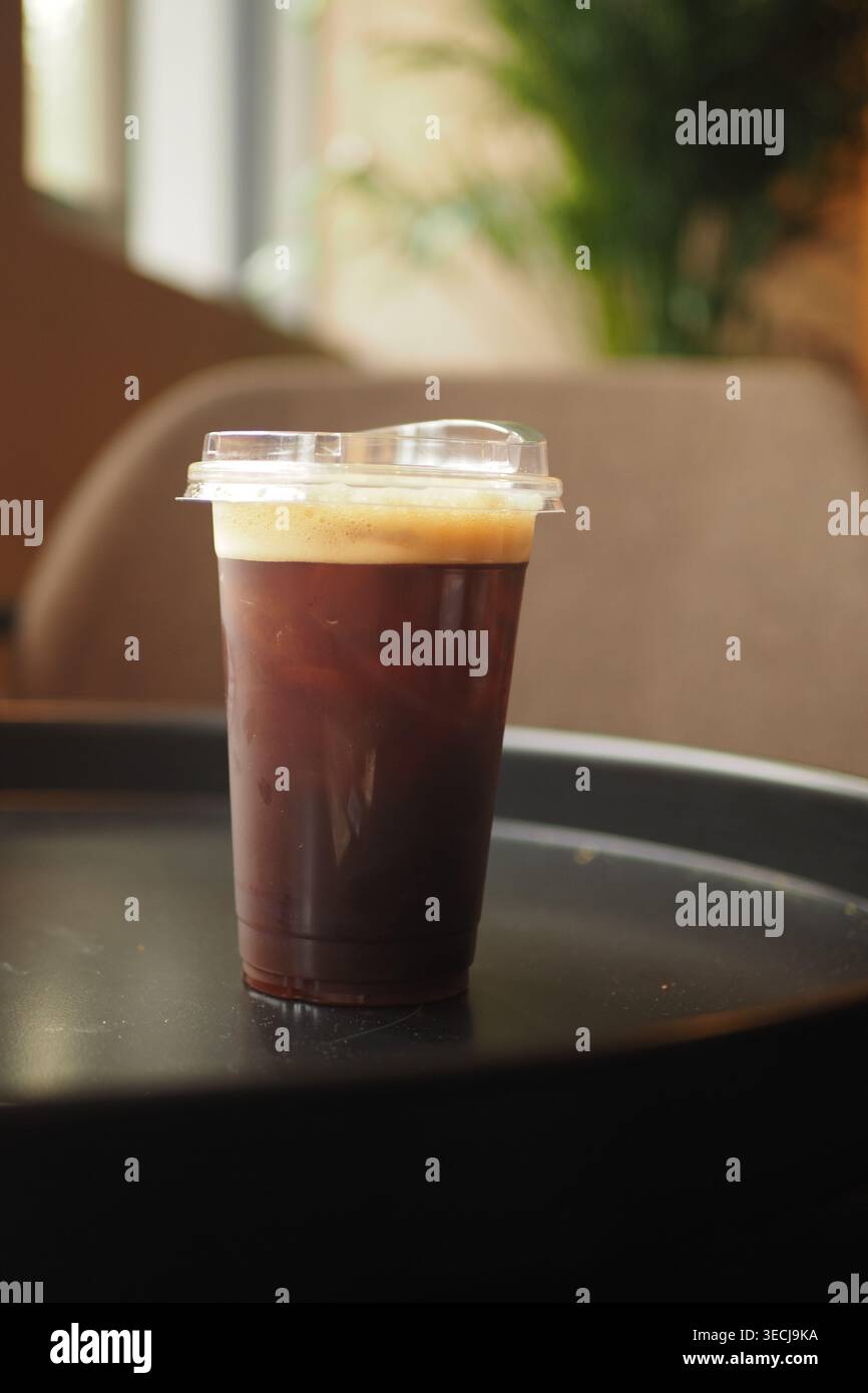 Kalter Kaffee, serviert in Plastikbecher auf einem Tisch Stockfoto
