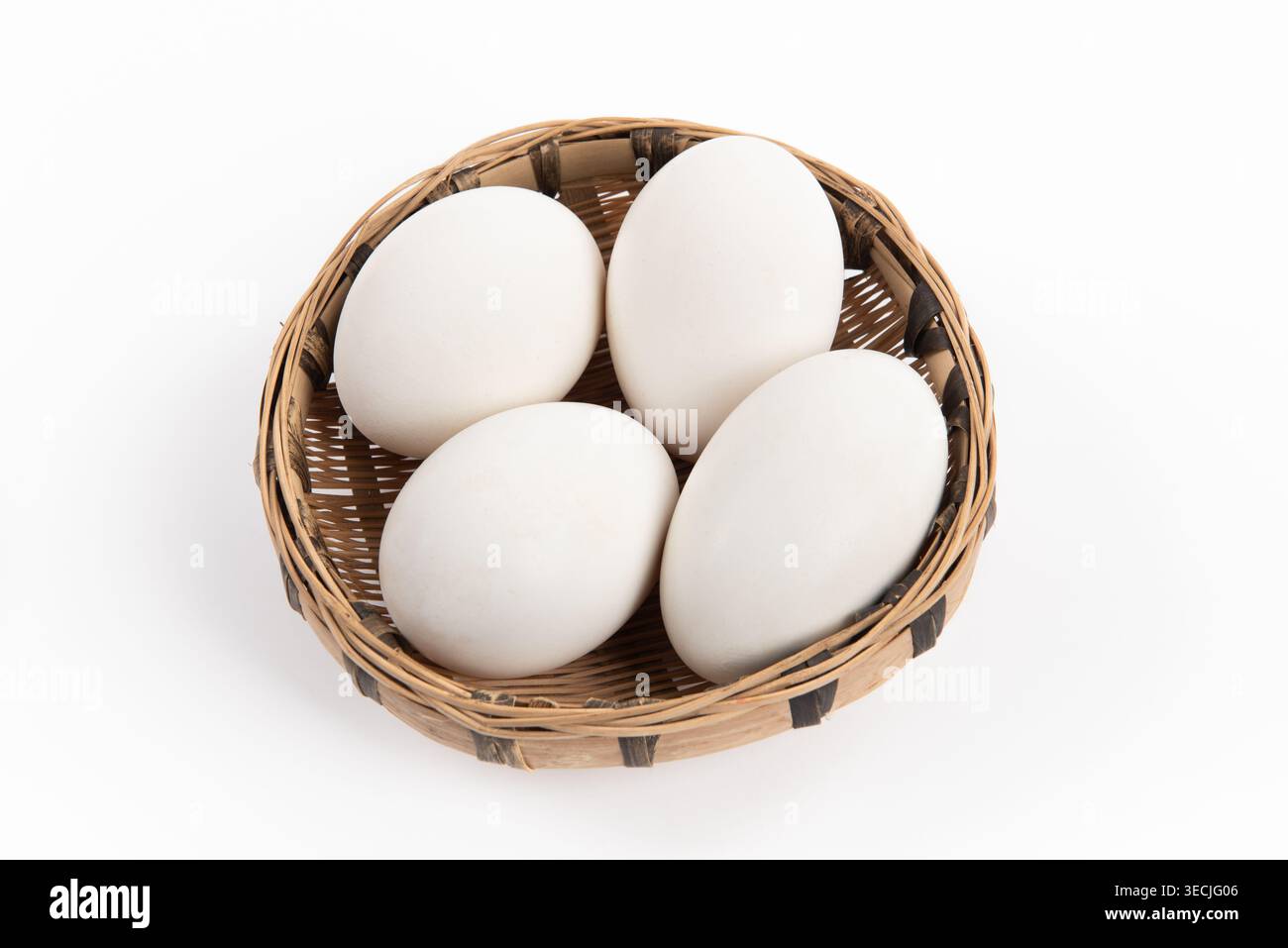 Vier große weiße Gänseeier liegen in einem kleinen Korb Stockfoto