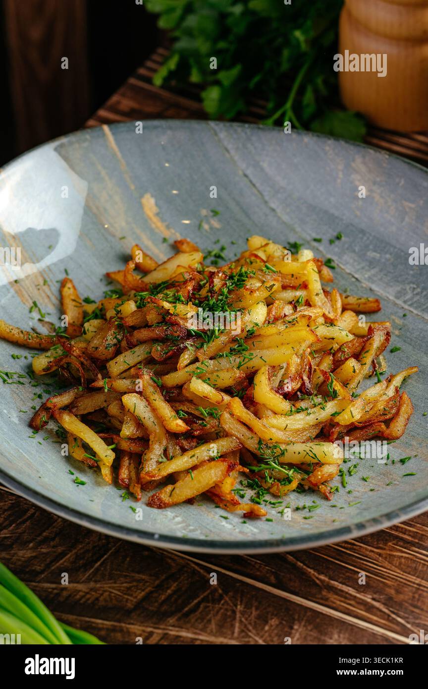Gebratene Kartoffeln mit Kräutern auf einem Teller auf dem Tisch Stockfoto
