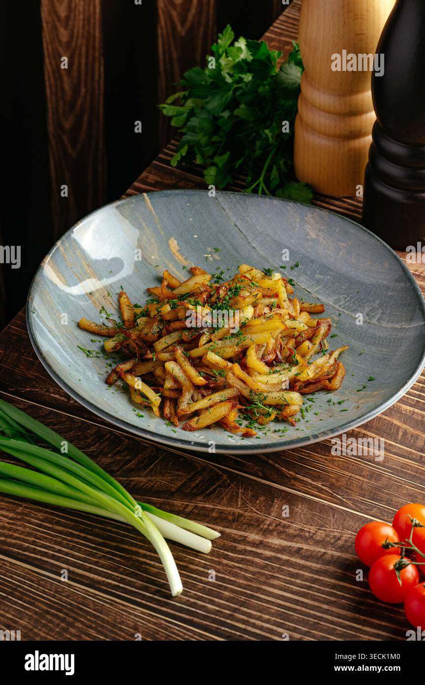 Gebratene Kartoffeln mit Kräutern auf einem Teller auf dem Tisch Stockfoto