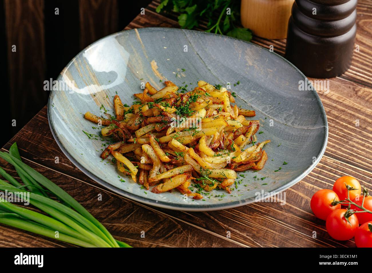 Gebratene Kartoffeln mit Kräutern auf einem Teller auf dem Tisch Stockfoto